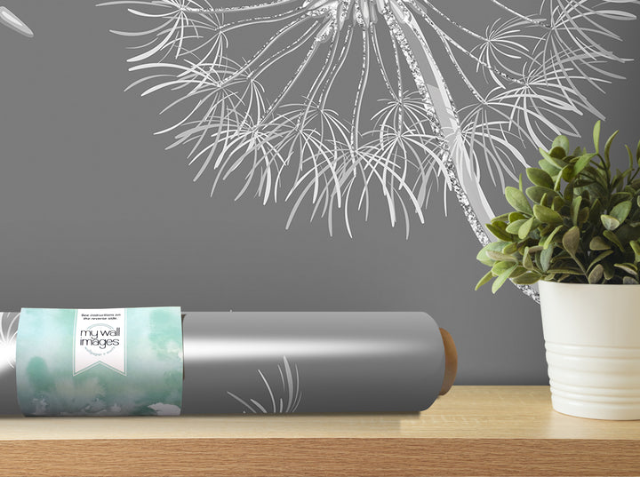 a grey roll of wallpaper with a watercolor-like design, placed on a wooden shelf next to a potted plant.