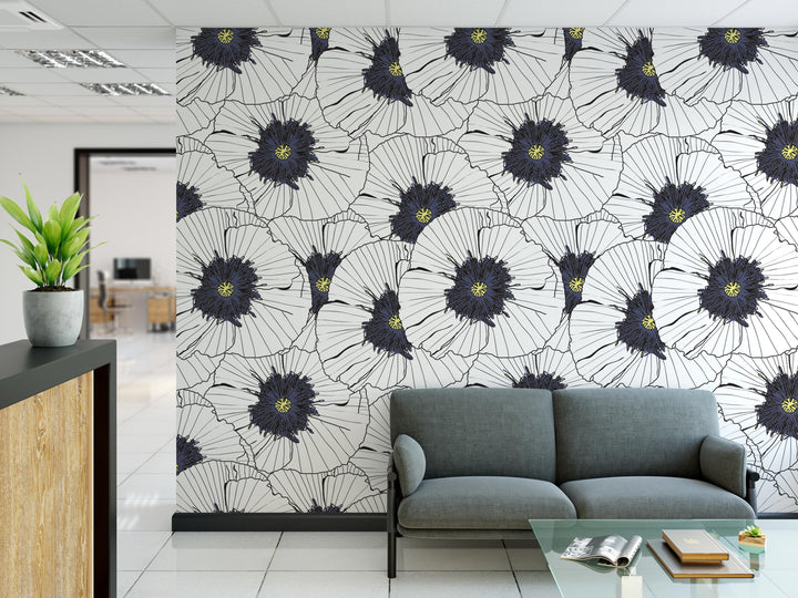 a modern office space with a large wall mural of white and black flowers, a gray sofa, and a glass coffee table.