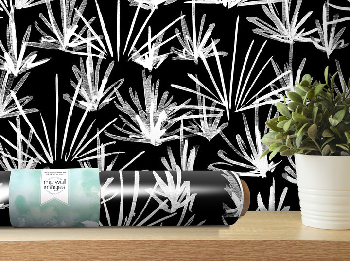 a black and white patterned wallpaper with a potted plant and a roll of wallpaper on a shelf.