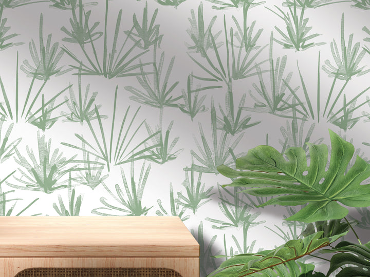 a wall with a repeating pattern of green palm leaves and a wooden table in the foreground.