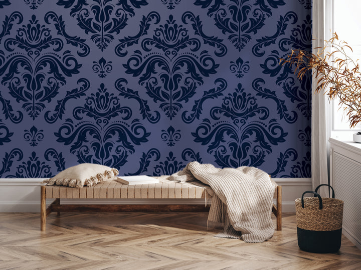 a dark blue wall with a repeating pattern of a floral design, a wooden bench with a white pillow and a woven basket, and a plant in a basket on the floor.