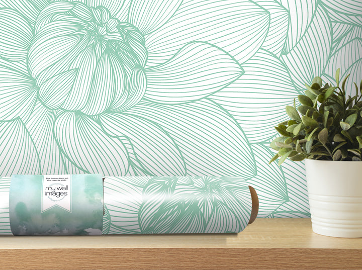 a wallpapered wall with a large green flower design, a roll of wallpaper, and a potted plant on a shelf.