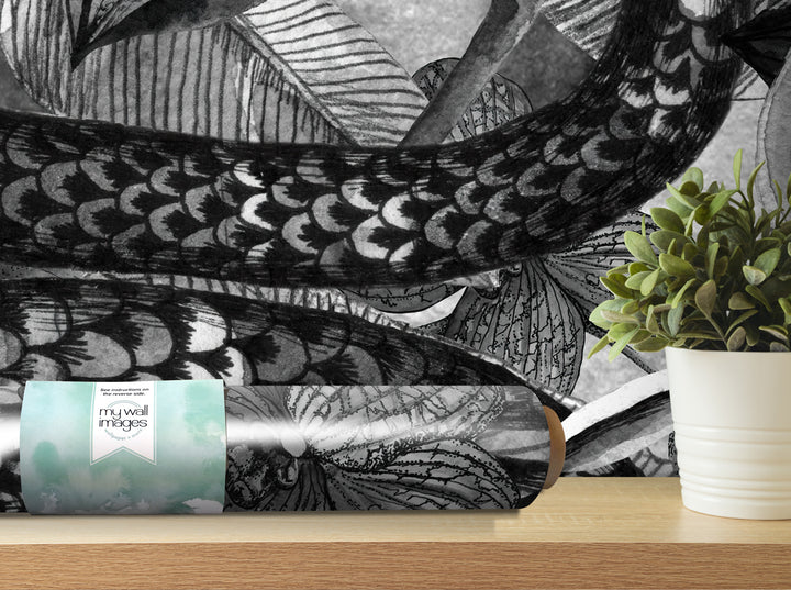 a roll of wallpaper with a black and white pattern, placed on a wooden shelf next to a potted plant.