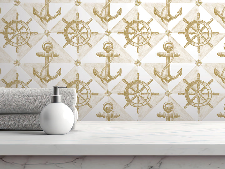 a bathroom counter with a white soap dispenser, a towel, and a white marble surface. The background is a wall with a repeating pattern of gold anchors and ship wheels, creating a nautical theme.