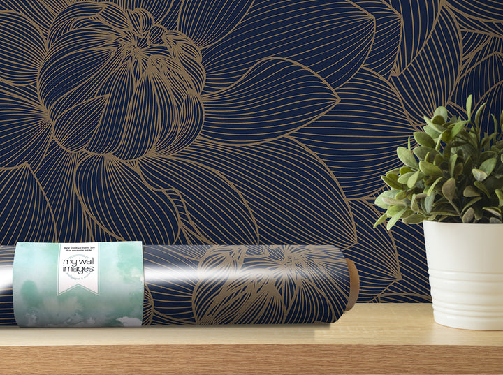 a dark blue wall with a gold floral pattern, a roll of wallpaper, a potted plant, and a wooden shelf.