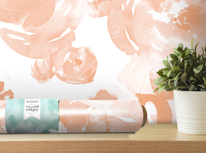 a roll of wallpaper with a watercolor-style pattern, placed on a wooden shelf next to a potted plant.