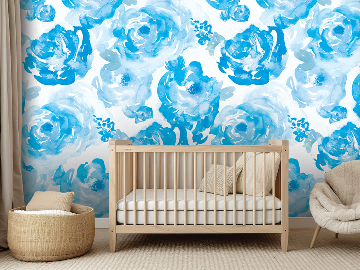 a nursery with a wooden crib, a beige chair, and a woven basket. The walls are decorated with a blue floral pattern, creating a serene and calming atmosphere.