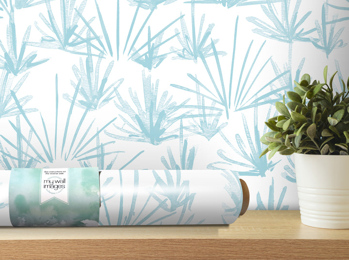 a roll of wallpaper with a blue and white pattern, placed on a wooden shelf next to a potted plant.