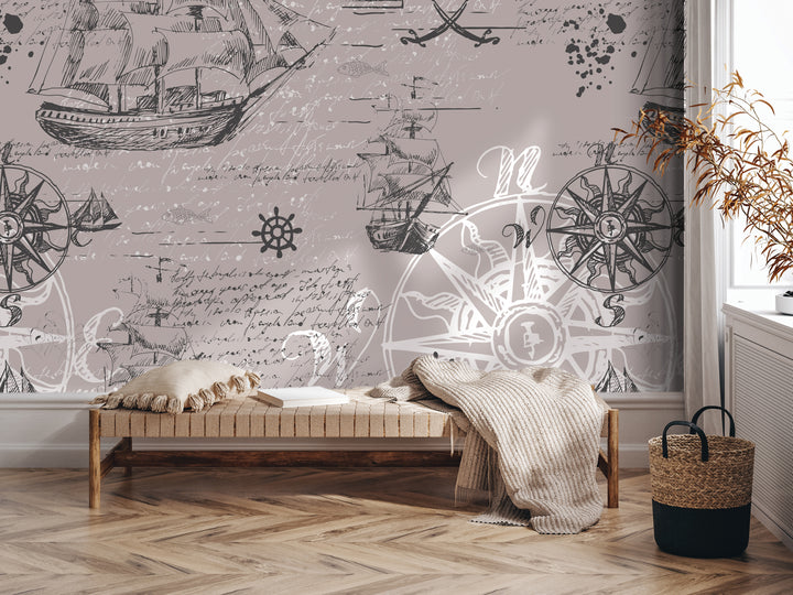 a room with a large wall mural depicting various nautical elements, including ships, a compass, and a ship's wheel. In the foreground, there is a bench with a blanket draped over it, and a woven basket is placed nearby. The overall setting appears to be a cozy and inviting space, with the mural serving as a focal point and adding a touch of maritime charm to the room.