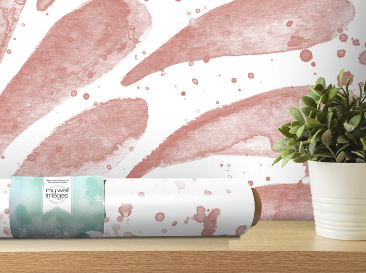 a white wall with a pink watercolor-style design, and there is a potted plant on a shelf next to it.