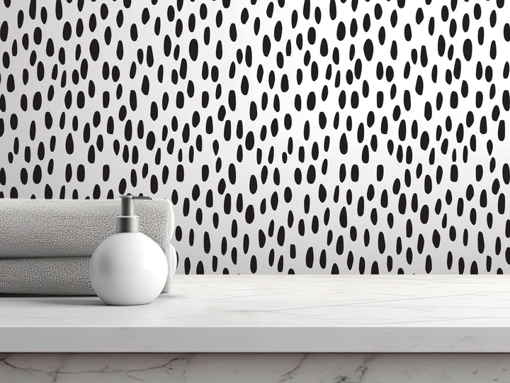 a white countertop with a white soap dispenser and a folded towel, set against a black and white polka dot patterned wall.