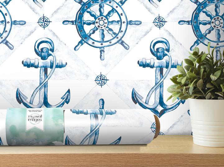 a wall with a blue and white nautical-themed wallpaper, including a ship's wheel and anchor. There is also a potted plant and a roll of wallpaper in the foreground.