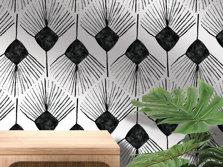 a black and white geometric pattern on a wall, with a wooden table in the foreground and a large green plant in the background.