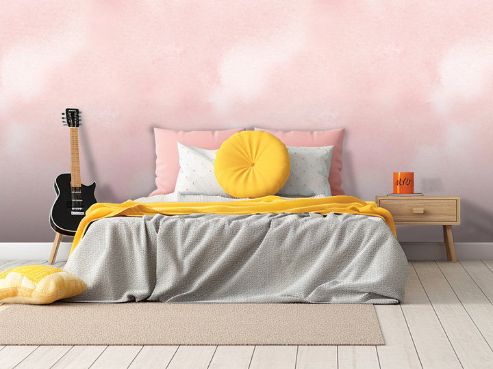 a bedroom with a bed, a guitar, and a nightstand. The bed has a gray comforter and a yellow throw pillow. The guitar is leaning against the wall, and the nightstand has a book and a mug on it. The walls are painted pink, and the floor is made of wood.