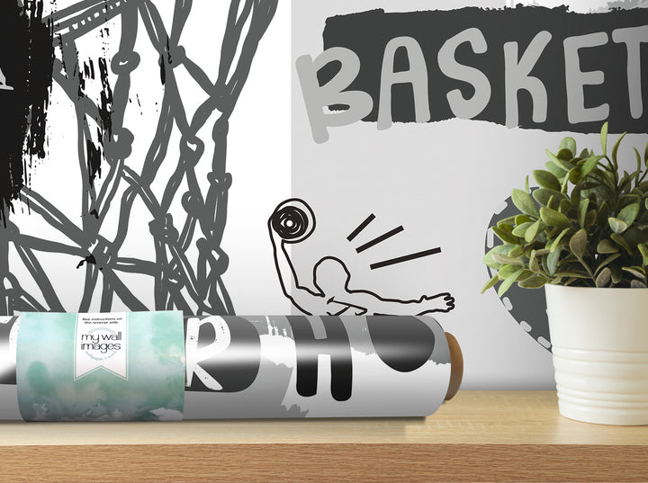a wall with a basketball-themed design, including a basketball hoop and a basketball player. There is also a potted plant and a roll of wallpaper with a basketball design on it.