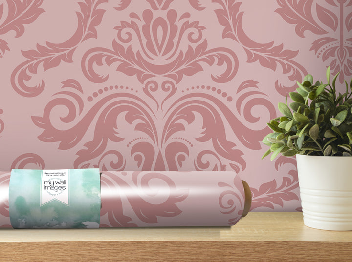 a pink damask wallpaper with a decorative floral pattern, a roll of wallpaper, and a potted plant on a wooden shelf.