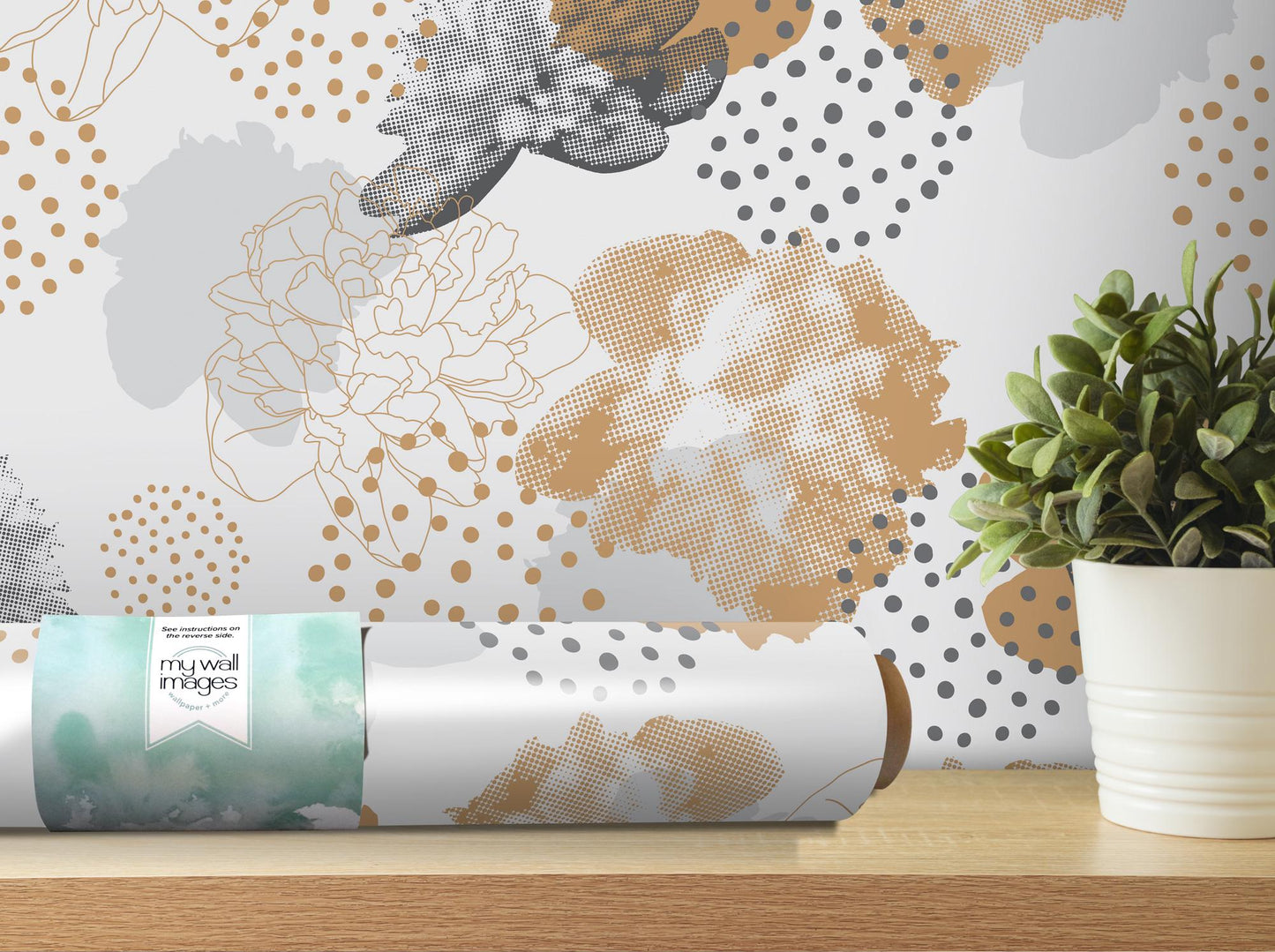 a vase with a plant on a table next to a roll of wrapping paper