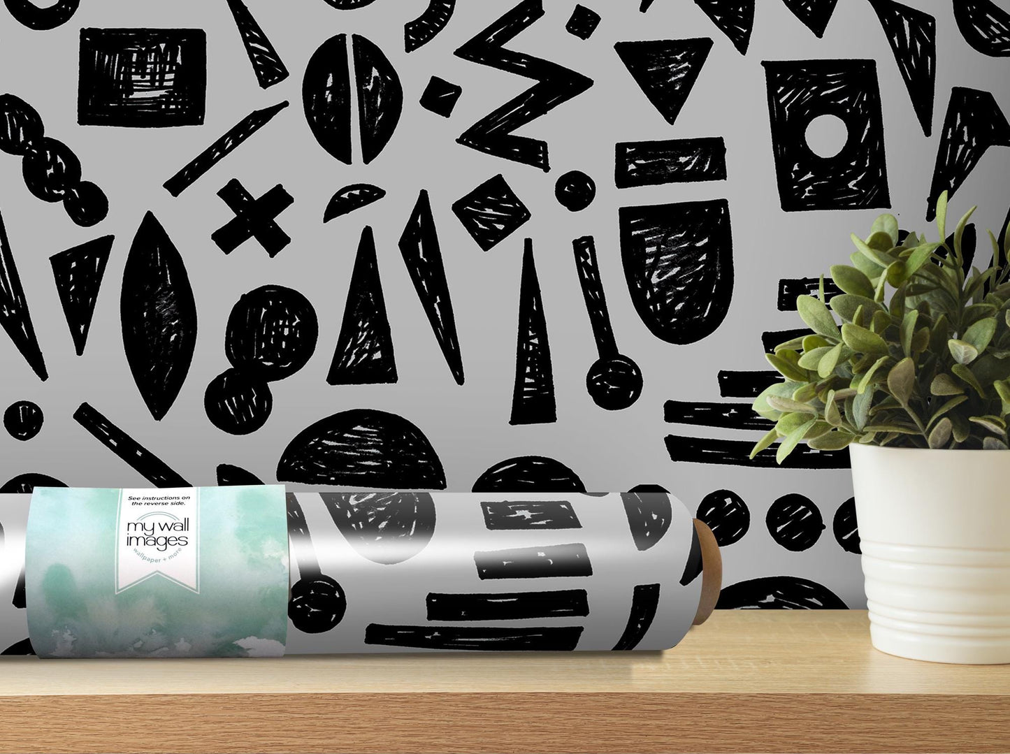 a black and white pattern on a wall next to a potted plant