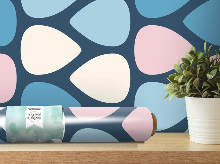 a vase with a plant on a table next to a roll of wrapping paper