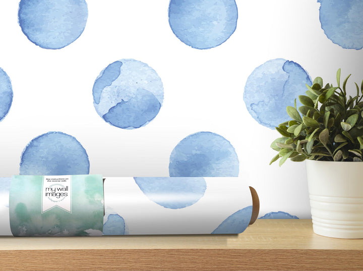 a vase with a plant on a table next to a roll of wrapping paper