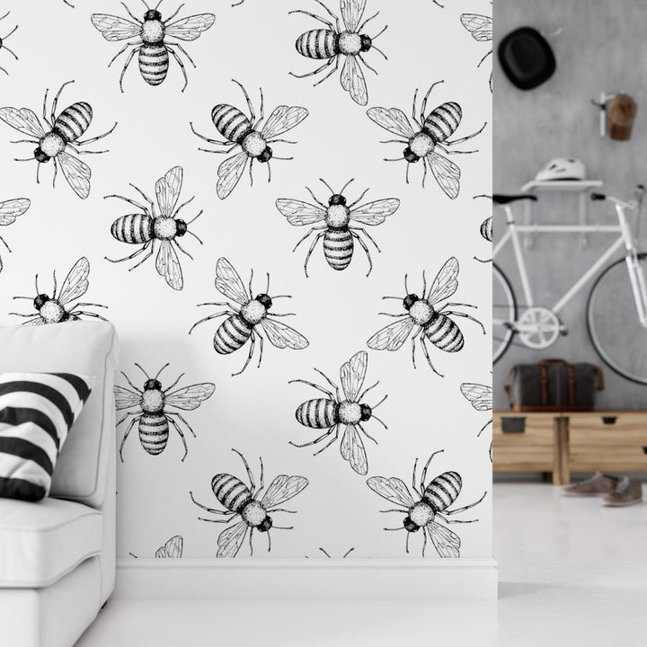 a living room with a white couch and a wall with black and white bees on