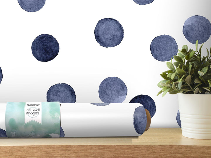 a white vase filled with a plant next to a blue polka dot wallpaper