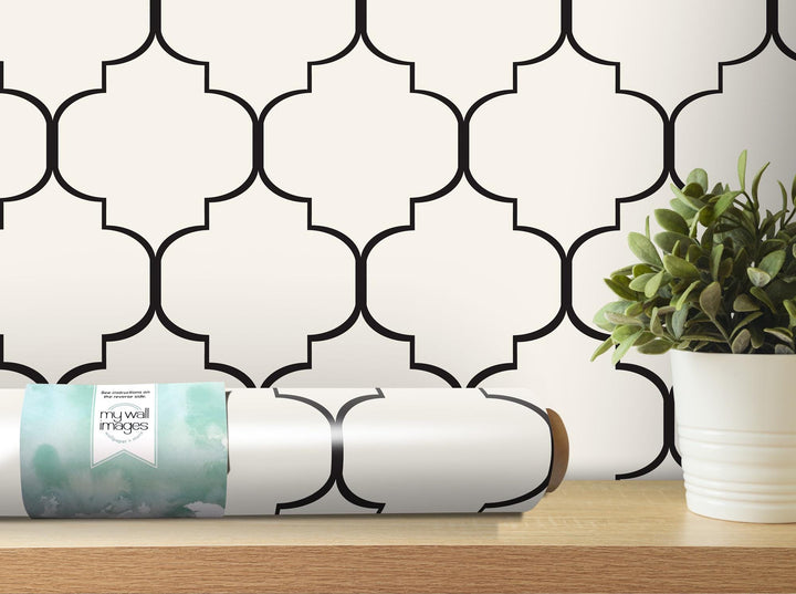 a white vase with a green plant on a table