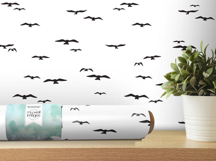 a white vase with a plant on top of a wooden table