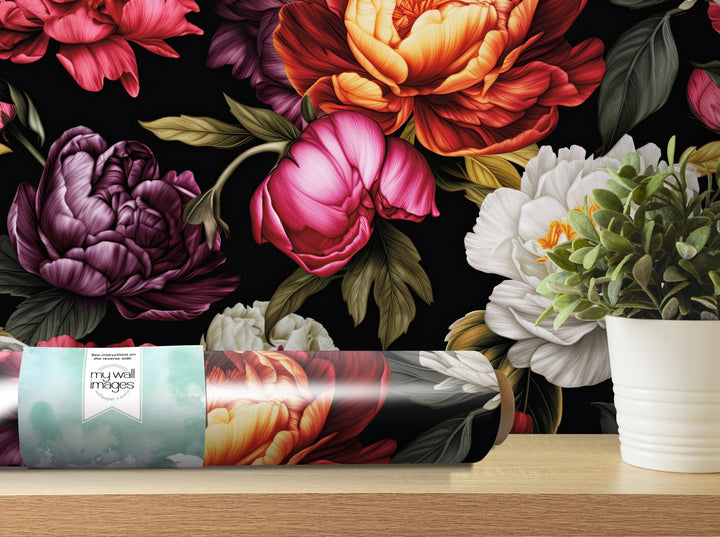 a vase of flowers sitting on a table next to a roll of wrapping paper