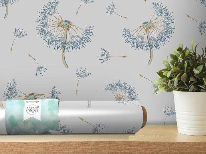 a wallpapered wall with a repeating pattern of dandelion-like flowers in shades of blue and green. A potted plant is placed on a wooden shelf next to the wallpapered wall, and a roll of wallpaper with a similar pattern is also visible.