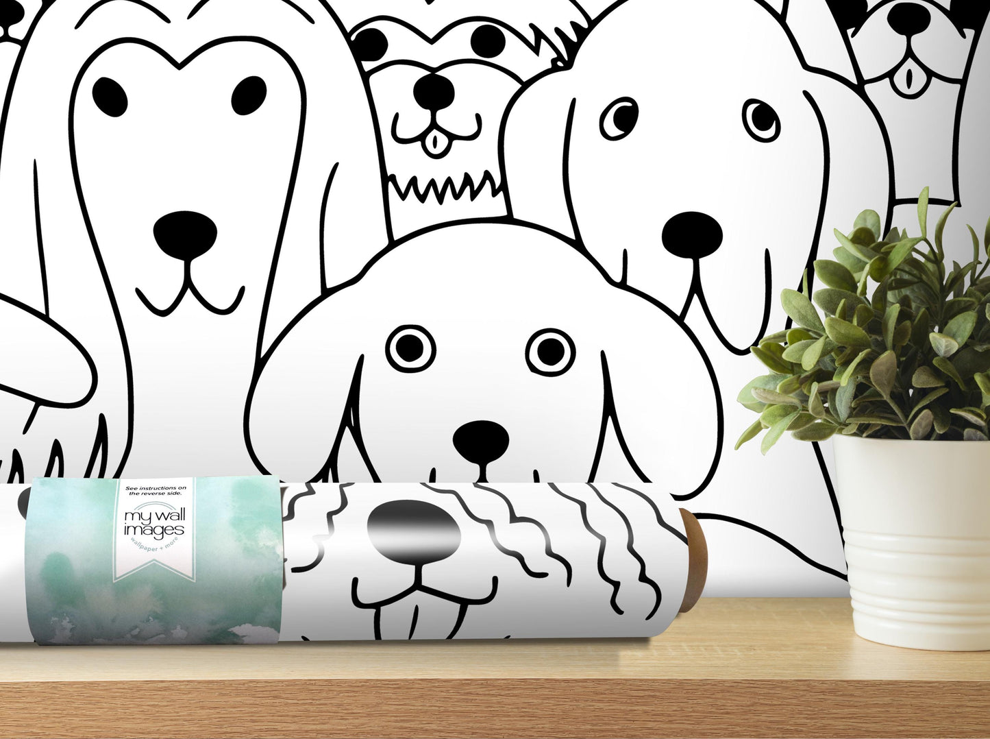 a roll of wall decals with a black and white dog illustration on it, placed on a shelf next to a potted plant.