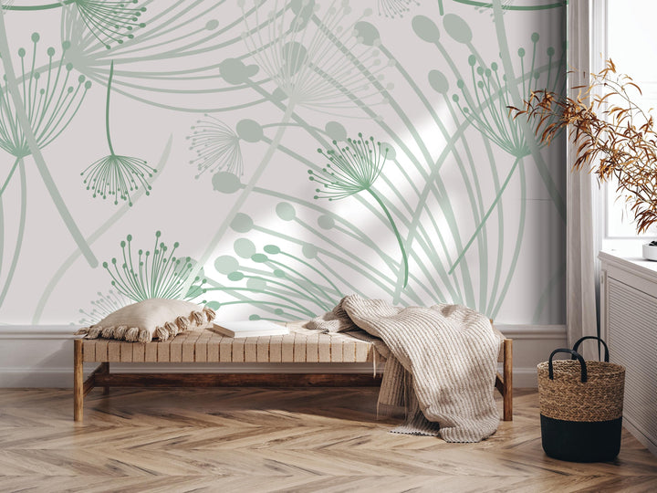 a modern and minimalist living room with a wooden floor and a white wall adorned with a green and white abstract floral pattern. In the room, there is a wooden bench with a beige blanket draped over it, and a woven basket next to it.