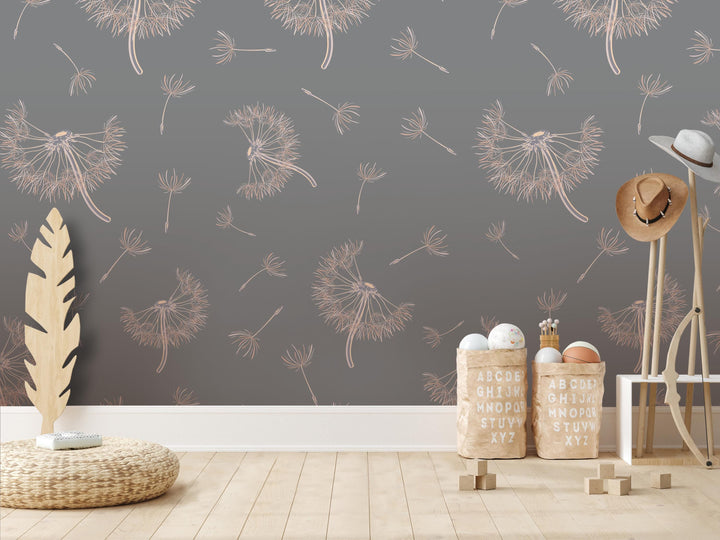 a room with a gray wall adorned with a repeating pattern of dandelion-like designs in white and beige. The room contains various objects, including a wooden hat stand, a woven basket, and a stack of wooden blocks. The overall scene appears to be a casual and relaxed setting, with the wall design and objects creating a harmonious and visually appealing composition.