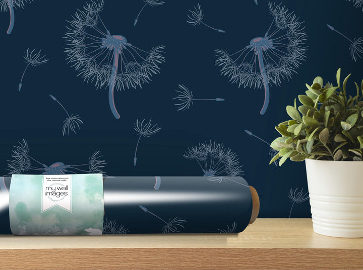 a dark blue wall with a repeating pattern of dandelion-like designs in white and blue, along with a potted plant and a roll of wallpaper on a wooden shelf.