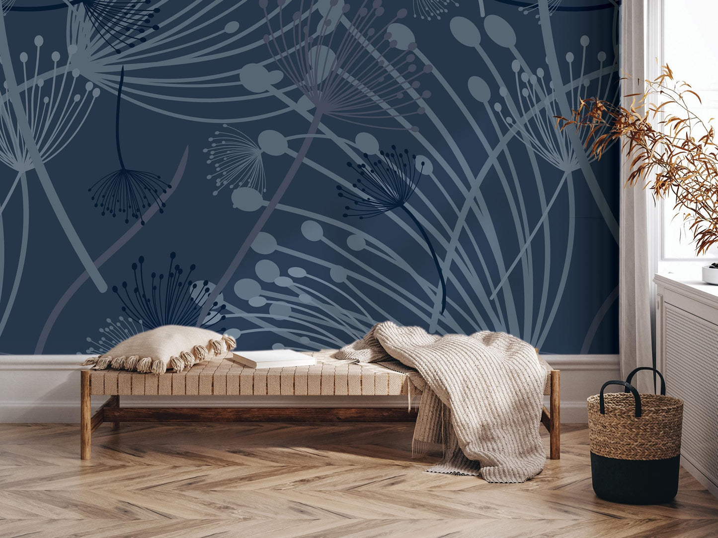 a modern living room with a dark blue wall adorned with a pattern of dandelions and other abstract designs. In the foreground, there is a wooden bench with a white pillow on it, and a woven basket next to it. The room also includes a window and a plant, adding to the overall aesthetic of the space.