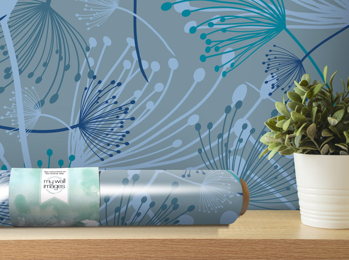 a wall with a blue and white abstract floral pattern, a roll of wallpaper with a similar pattern, and a potted plant on a shelf.