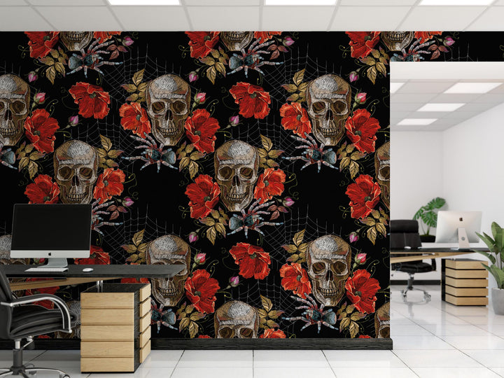 a modern office space with a striking black and red floral pattern on the wall behind a desk. The pattern includes skull and rose motifs, as well as other floral elements. The desk has a computer monitor and a chair, and there is a plant in the corner of the room.