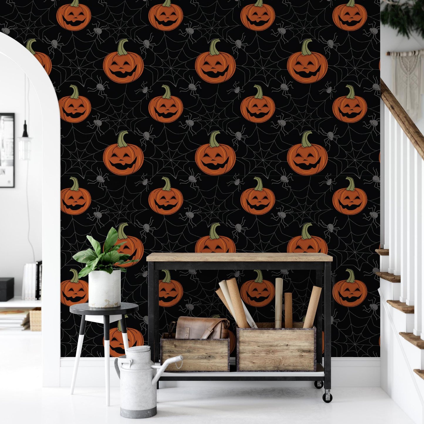 a wall with a Halloween-themed wallpaper, including jack-o-lanterns and spider web patterns. In front of the wall, there is a small table with a plant and a white watering can.