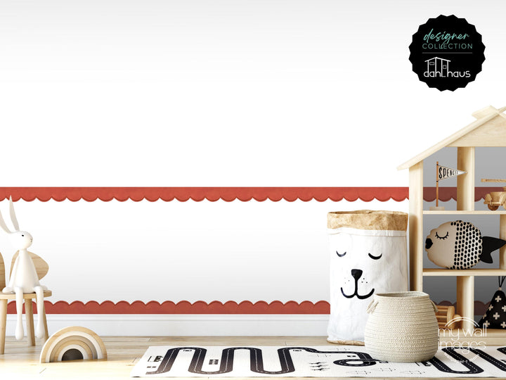 A child's room with a wooden dollhouse, a toy car, and a basket with a face on it, all set against a white wall with a red scalloped edge.