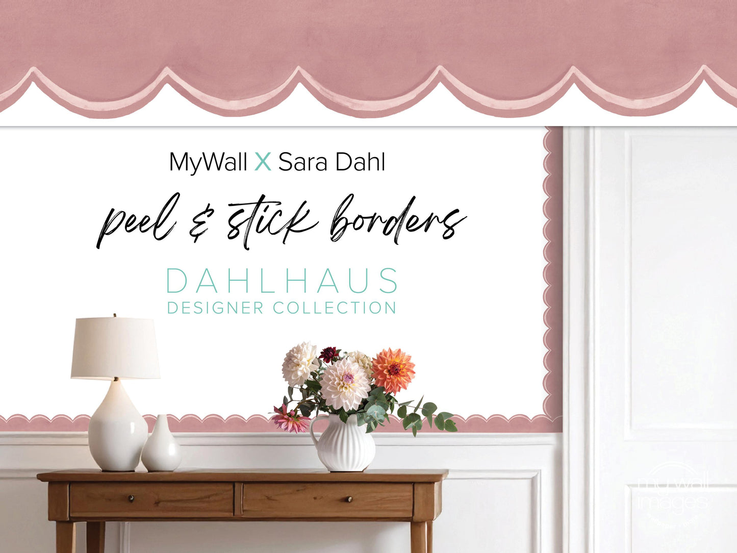 a wooden table with a vase of flowers, a lamp, and a pink decorative border on the wall behind it.