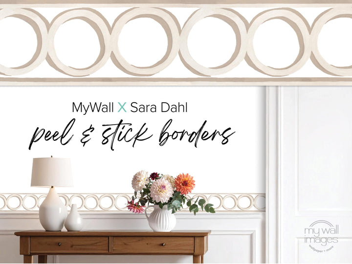 a wooden table with a vase of flowers, a lamp, and a decorative border along the wall.