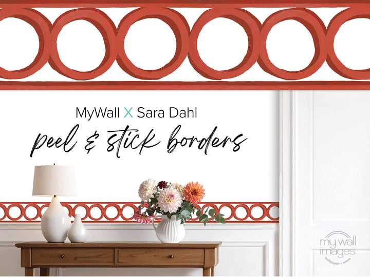 a wooden table with a vase of flowers, a lamp, and a red circular border with a repeating pattern.