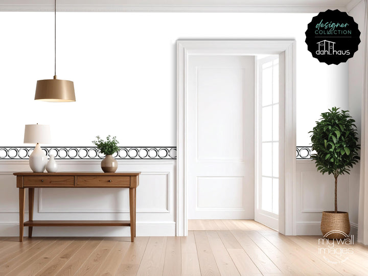 a modern and minimalist living room with a wooden console table, a lamp, and a potted plant. The room has a clean, white color scheme and features a large window that allows natural light to fill the space.