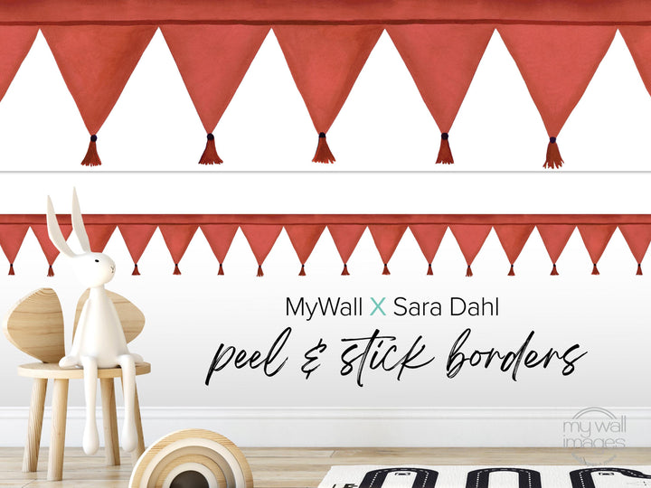 a white rabbit sitting on a wooden chair, with a red and white striped border behind it. The wall behind the rabbit has a repeating pattern of red and white triangles, creating a festive and playful atmosphere. The text "MyWall X Sara Dahl Peel & Stick Borders" is displayed on the wall, indicating the type of border used.