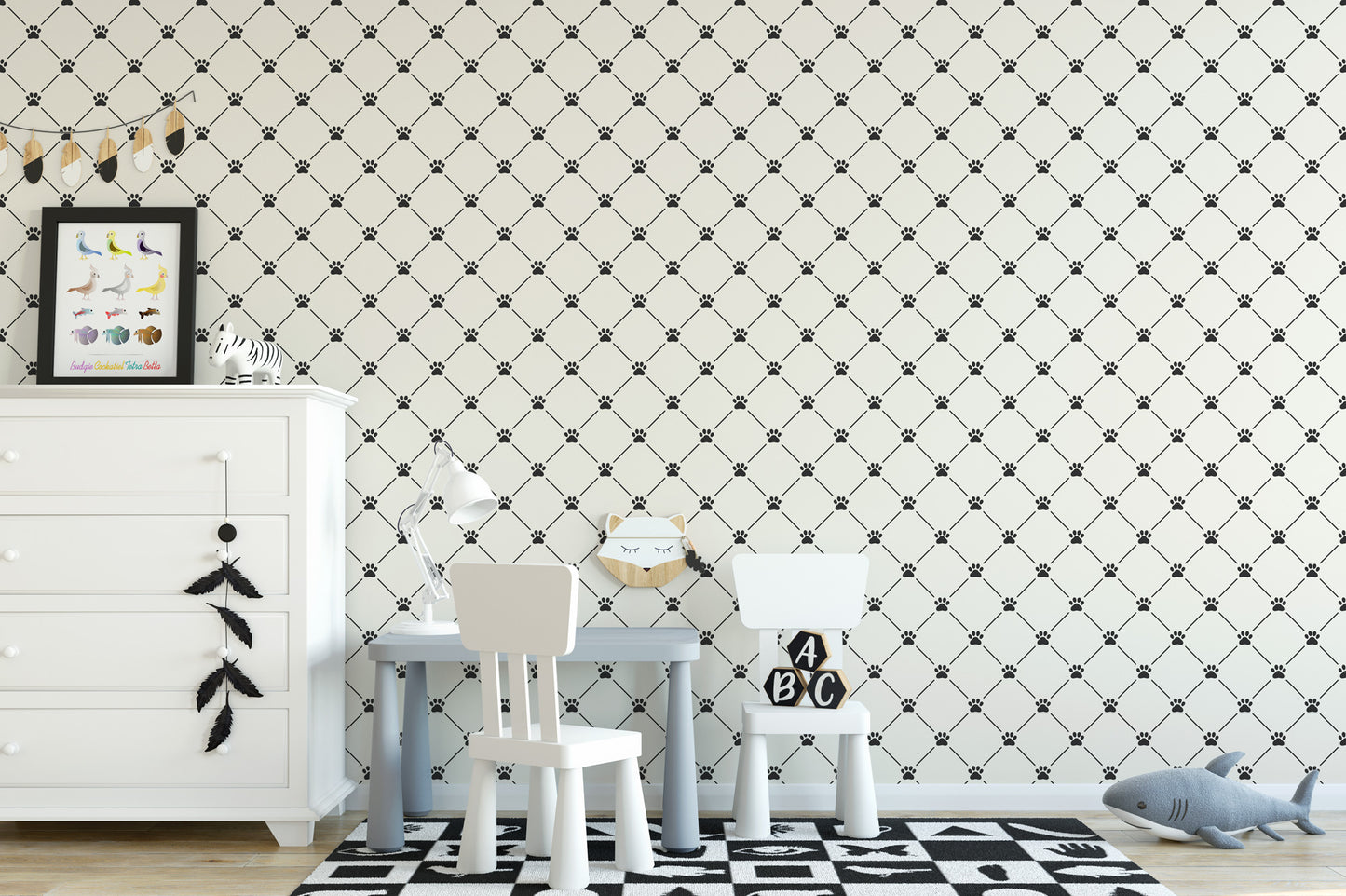 a child's room with a black and white checkered pattern on the walls, a white dresser, a small table with a lamp, and two white chairs. There is also a framed picture on the dresser and a stuffed animal on the floor.