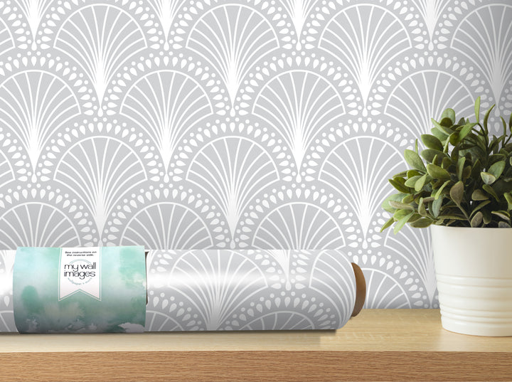 a wallpapered wall with a repeating pattern of white and gray designs, and a potted plant placed on a wooden shelf next to the wallpapered wall.