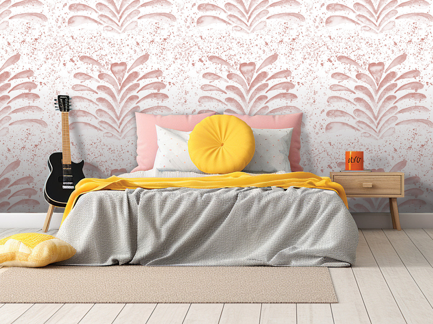 a bedroom with a bed, a guitar, and a nightstand. The bed has a gray comforter and a yellow throw pillow. The guitar is leaning against the wall, and the nightstand has a book and a mug on it. The wall behind the bed has a pink and white floral pattern.