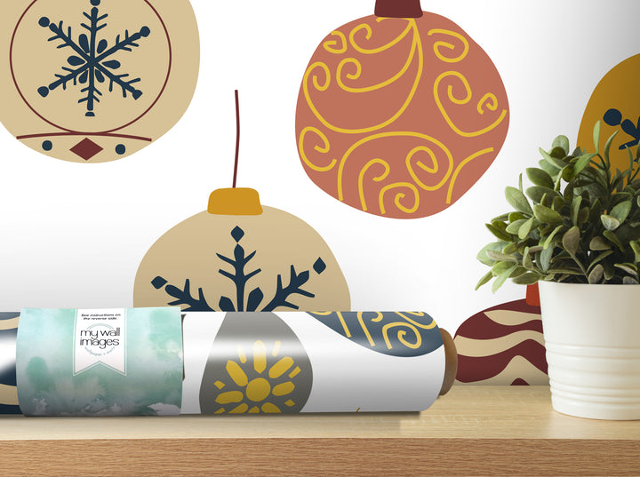 a wall with various decorative ornaments, including a snowflake, a ball, and a plant, as well as a roll of wallpaper or decal paper on a shelf.