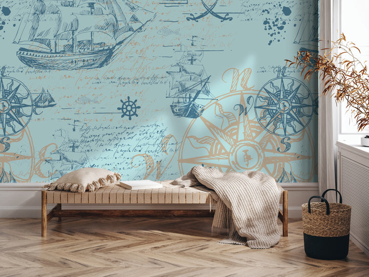 a room with a large mural depicting nautical scenes, including ships, a compass, and a ship's wheel. The room has a wooden floor and a bench with a blanket draped over it. There is also a woven basket on the floor next to the bench.