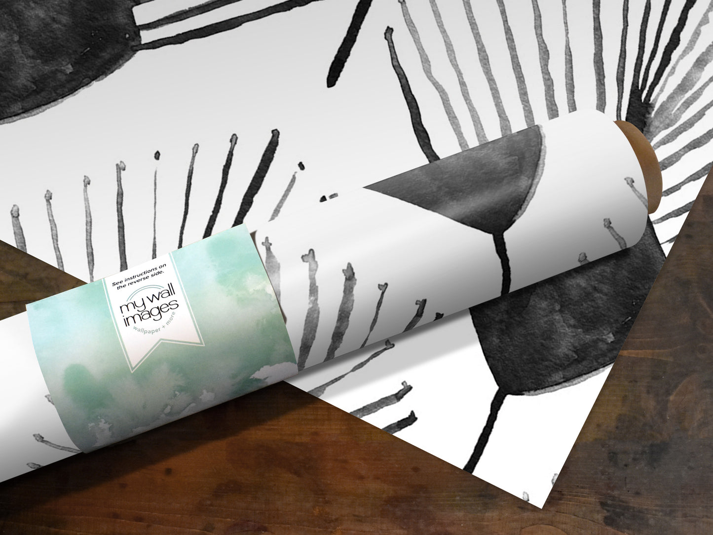 A roll of wallpaper with a black and white abstract design printed on it, placed on a wooden surface.